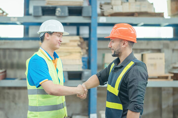 Warehouse worker shaking hands with his colleague at the industrial storage, Worker in uniform shaking hands with foreman at factory warehouse