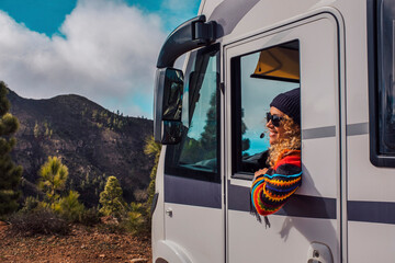 One female driver smile and enjoy travel destination outside the window of her modern big camper van motor home. Alternative vehicle for transport and vacation or tiny house for van life lifestyle