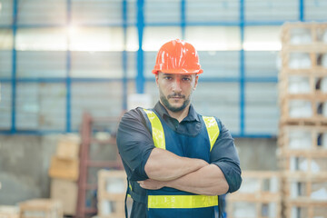 The male commander's smile stood in the warehouse with his arms crossed, looking at the camera. Logistics industry concept.