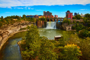 Rochester skyline along river and cliffs with waterfall pouring past bridge