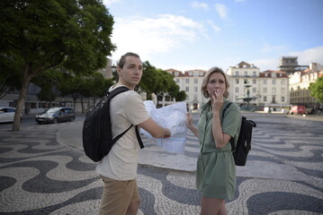 Fototapeta premium Frustrated tourist couple on square. Man and woman looking back with map in hands. Portrait, travelling concept