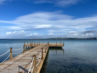 Fototapeta premium Empty wooden pier at the blue sea, beautiful sea horizon, transparent water