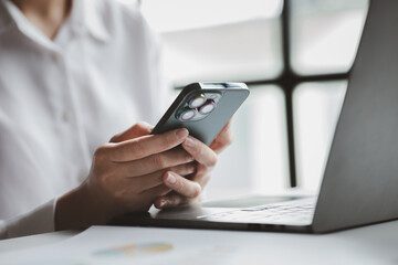 Business man looking at financial information from a mobile phone, he is checking company financial documents, he is an executive of a startup company. Concept of financial management.