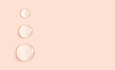 round drops of transparent gel serum on beige background