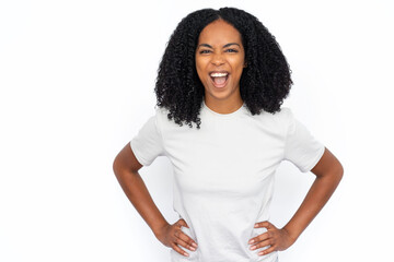 Happy multiracial woman screaming. Excited young female model with dark curly hair in white T-shirt looking at camera with hands on waist, shouting loudly in excitement. Advertisement concept