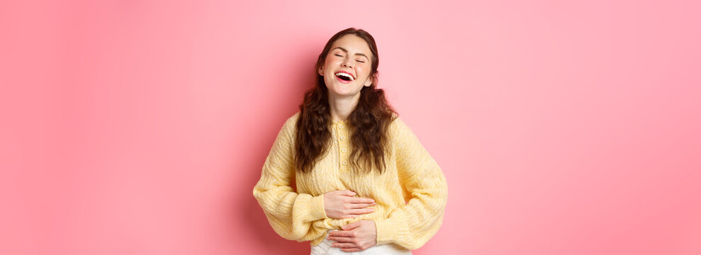 Image Of Carefree Beautiful Girl Laughing Out Loud, Touching Her Belly While Chuckling Over Funny Comedy, Hilarious Joke, Standing Against Pink Background