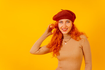 Red-haired woman in a red beret on a yellow background, studio shot, looking at the camera