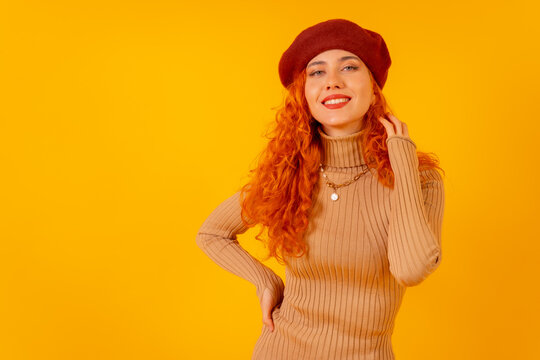 Red-haired woman in a red beret on a yellow background, studio shot, copy space