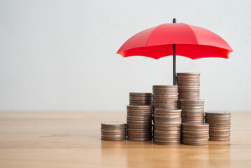 Stacked coins is protected by red umbrella on wooden table white wall background copy space. Assets wealth, money saving or money investment protection, security by insurance concept. Risk management. - obrazy, fototapety, plakaty
