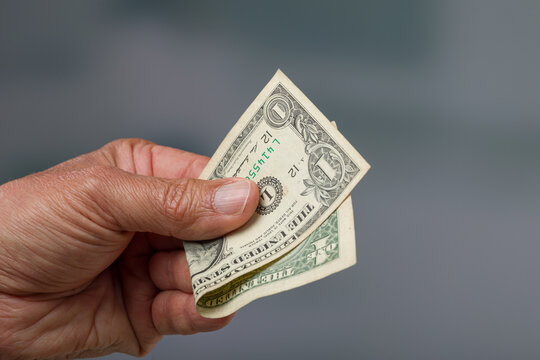 close-up of a man's hand giving a one dollar bill as tip