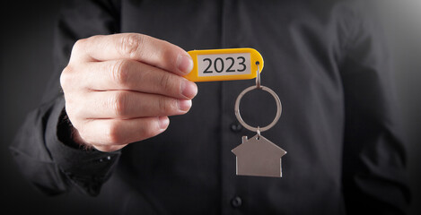  Man showing 2023 Happy New Year with house model.