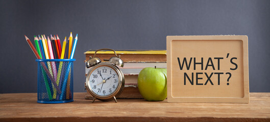 What's next message with a alarm clock, book, apple, pencils.