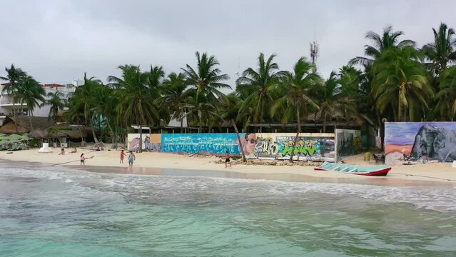man running on white sand beach in Playa Del Carmen Mexico on cloudy morning, aerial
