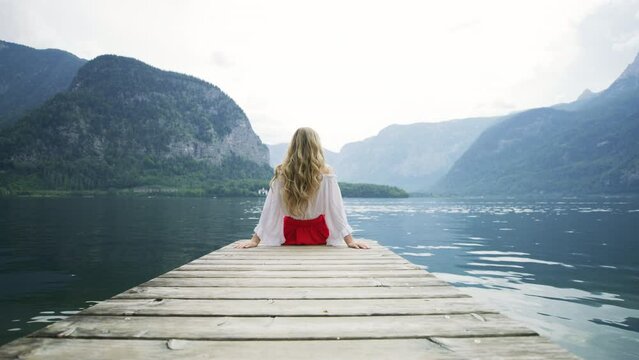 Woman sitting on a pontoon by Hallstatter See, Austria