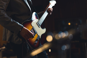 Cropped shot of guitarist holding electric guitar. Indoor shot of unrecognizable caucasian guitarist in a blazer holding professional guitar. High quality photo