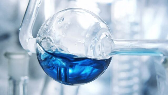 Spherical flask. Boiling and air bubbles in water. Blue liquid in glass of  flask.  Cosmetics and perfumes. Extract from ingredients. Aromatherapy. Сlearing process. Boiling.