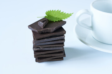 Bitter chocolate with mint and part of a mug on a white background.
