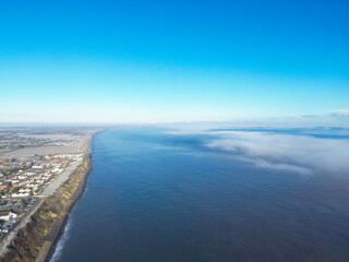 Large fog bank seen coming in from the sea and about to engulf a coastal town on the Suffolk coast during winter.