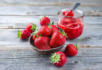 Reife rote Erdbeeren aus biologischem Anbau und Marmelade angeboten als close-up auf altem...