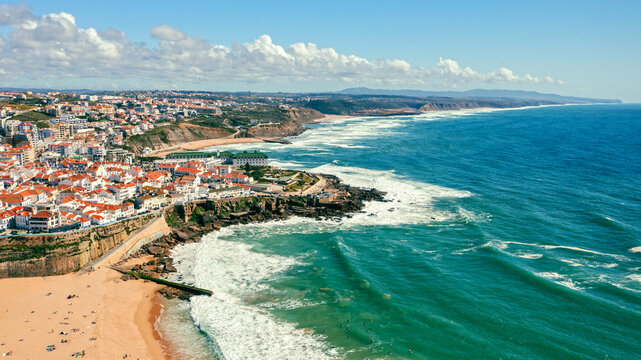 Aerial view of a beautiful tourist town located on the sandy beach of the Atlantic Ocean. Panorama of the city from drone with a rocky ocean coastline. Scenic cityscape from drone on ocean coast