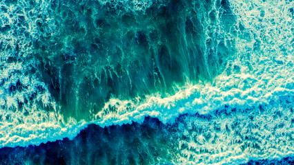 Beautiful  blue ocean waves - aerial view. Top view to the beautiful azure water sea surface.  Atlantic Ocean, Portugal. Drone view of rolling waves with white foam on the summer sunny day.