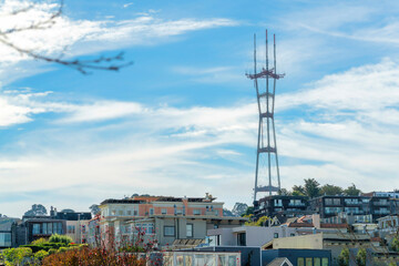 Sutro tower in neighborhood with houses and homes with trees and foliage in the city with blue and white cloudy sky background
