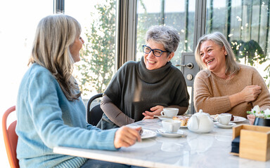 Group of elderly women have breakfast in a cafeteria, three retired female friends are celebrating...