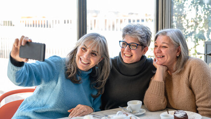 group of elderly women have breakfast in a cafe and enjoy taking photos for social networks, women...