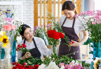 Millennial Asian young female flower shopkeeper decorator florist worker in apron smiling holding...