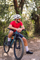 smiling young cyclist resting during his mountain bike training ride, concept of freedom and sport in nature