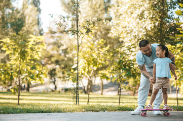 Obraz premium Dad teaching his daughter to ride a skate board