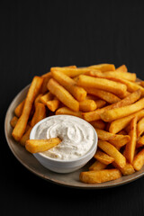 Homemade French Fries with Ranch Dressing on a Plate on a black background, side view.