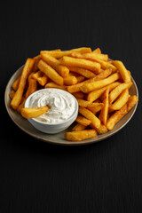 Homemade French Fries with Ranch Dressing on a Plate on a black background, side view.