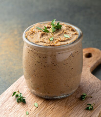 Close up of a jar with  fresh homemade liver pate garnished with thyme