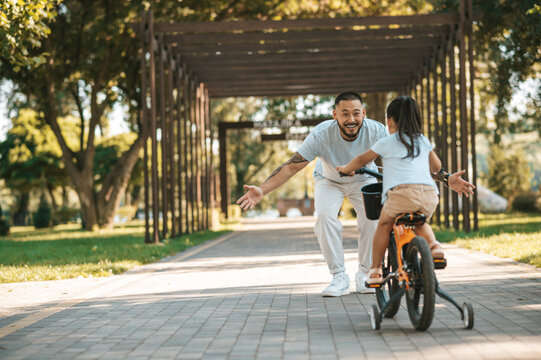 Dad and a gitl looking happy spending time in the park and riding a bike
