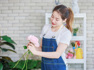 Asian young professional female flower shopkeeper decorator florist wearing jeans apron standing...