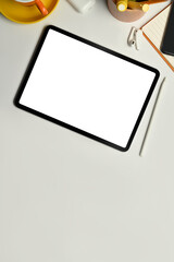 Flat lay digital tablet with blank screen, cup of coffee cup and notepad on white office desk