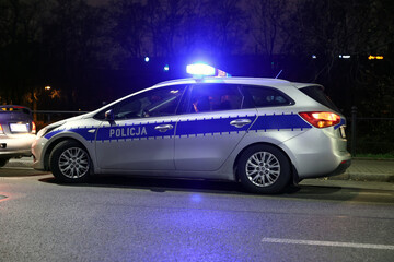 Aresztowanie przez policji wieczorem w mieście. - Sygnalizator błyskowy niebieski na dachu radiowozu policji polskiej w nocy.
 - obrazy, fototapety, plakaty