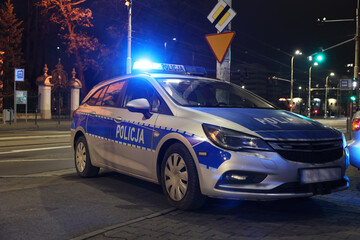 Aresztowanie przez policji wieczorem w mieście. - Sygnalizator błyskowy niebieski na dachu radiowozu policji polskiej w nocy.
 - obrazy, fototapety, plakaty