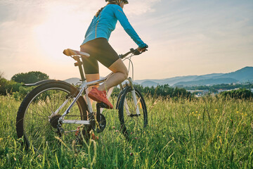 Fototapeta na wymiar Cyclist Woman riding bike in helmets go in sports outdoors on sunny day a mountain in the forest. Silhouette female at sunset. Fresh air. Health care, authenticity, sense of balance and calmness.
