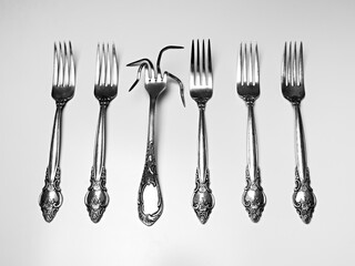 set of silver antique forks with one deformed fork isolated on white background