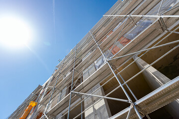 Fototapeta premium Bottom shot on unfinished edifice with scaffold and yellow pipe for disposal industry garbage