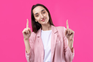 Happy young caucasian female in a pink jacket pointing fingers away