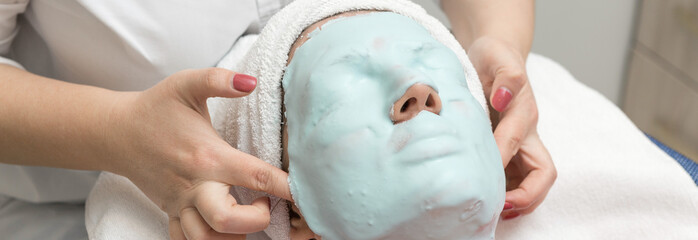Face skin care. Beautician applying beauty oil mask on face using brush In spa salon