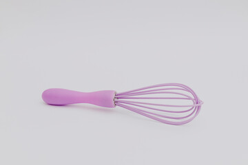 Purple whisk for the kitchen on a white background