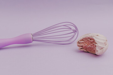 Purple kitchen whisk with marshmallow purple, on purple background