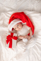 cute baby in Santa hat at home in bed. The first New Year. Christmas Gift