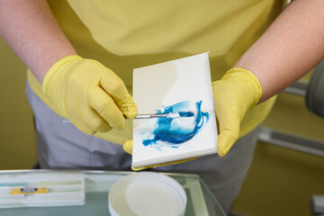 The orthodontist prepares a special paste for making an impression of the patient's teeth
