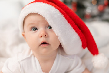 cute baby in Santa hat at home in bed. The first New Year. Christmas Gift