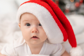 cute baby in Santa hat at home in bed. The first New Year. Christmas Gift